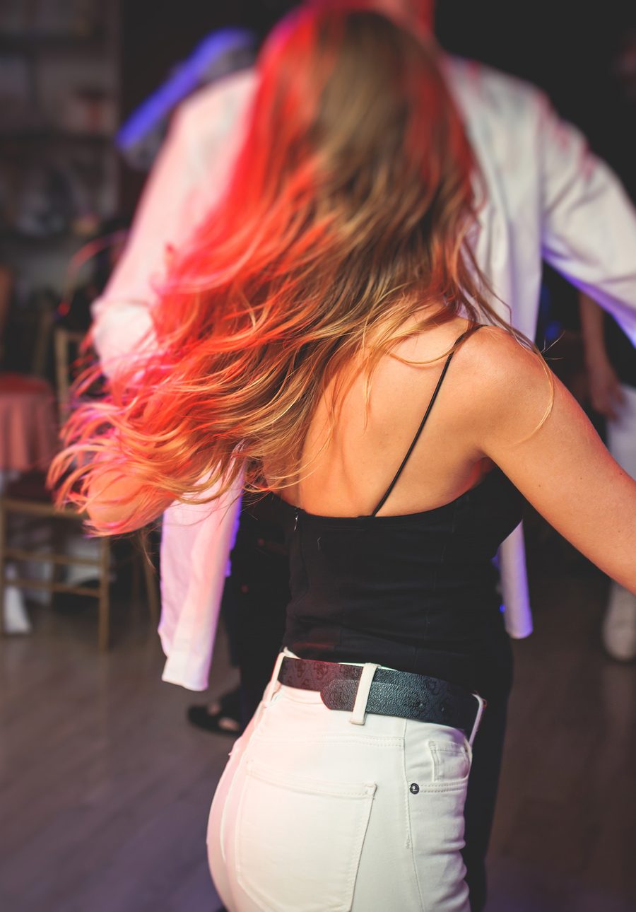 A woman turning under her partner’s arm at a dance party, her long hair flying