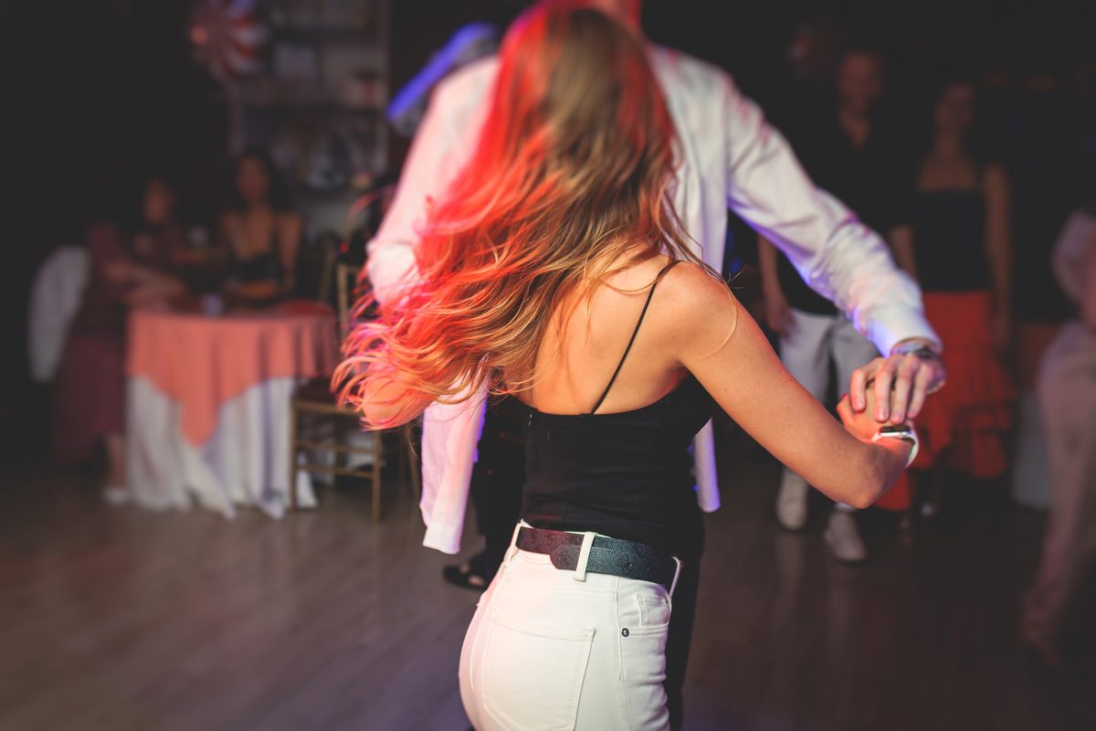 A woman turning under her partner’s arm at a dance party, her long hair flying