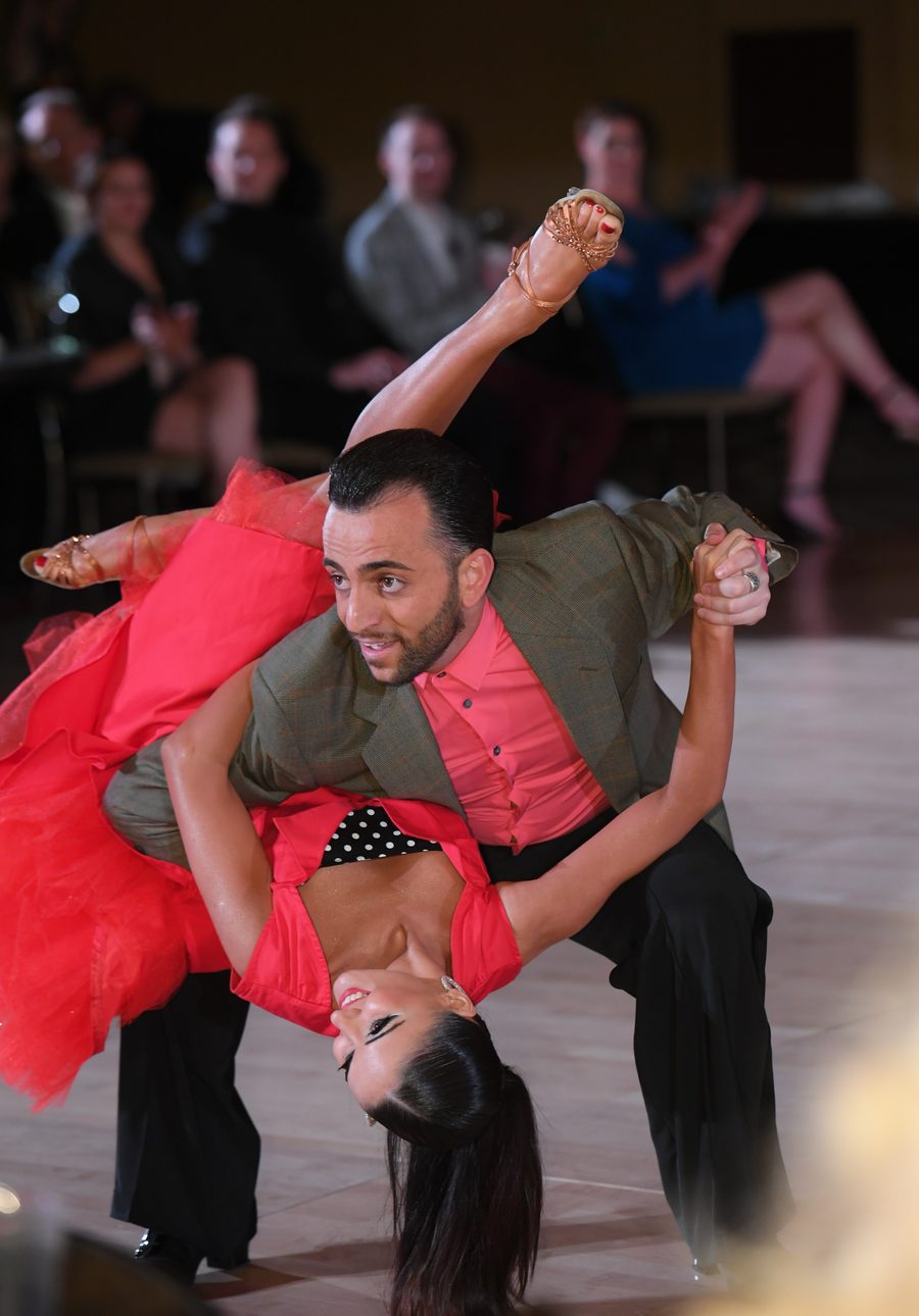 Vard Margaryan dipping his partner in a red swing dress low to the floor at a dance event
