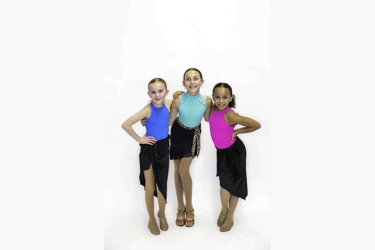 Three young dancers in bright Latin dance tops and black skirts