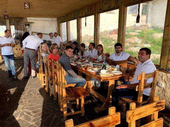 The party seated along one long wooden table at an open-air restaurant