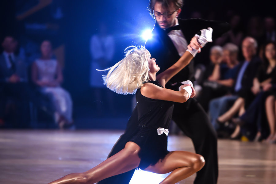 A couple in a dramatic Latin line on a competition floor in front of an audience