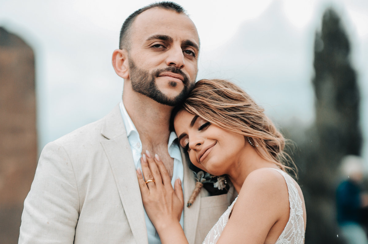 A bride resting her head on her groom's shoulder, her hand on his chest