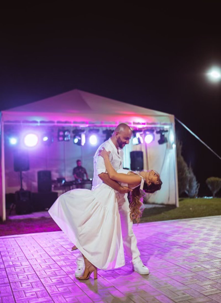 A couple in a deep dip at the end of their dance on an outdoor floor at night