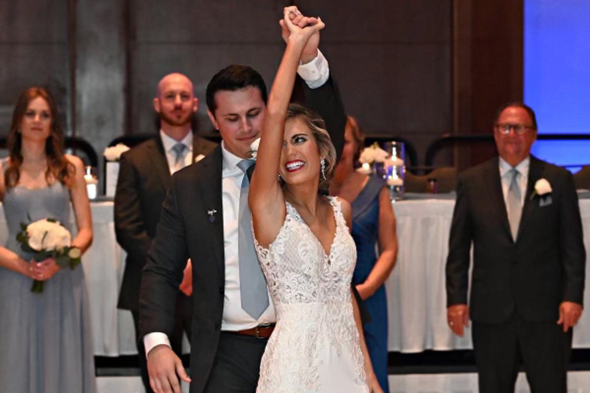 A groom turning his bride under his arm on the dance floor as the wedding party looks on
