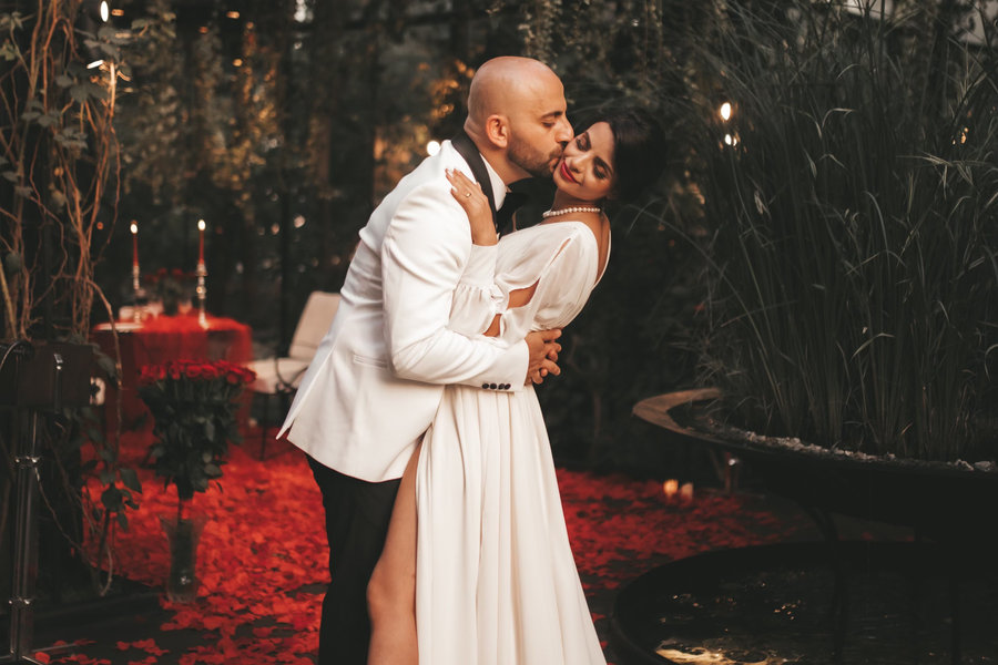 A bride and groom dancing together among scattered rose petals