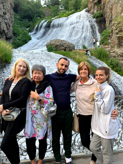 Five of the group in front of a wide waterfall falling over a mossy rock face