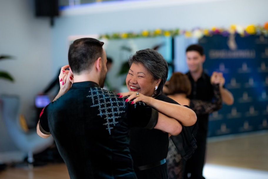 A smiling student dancing in closed hold with her partner at VM Ballroom Dance Studios