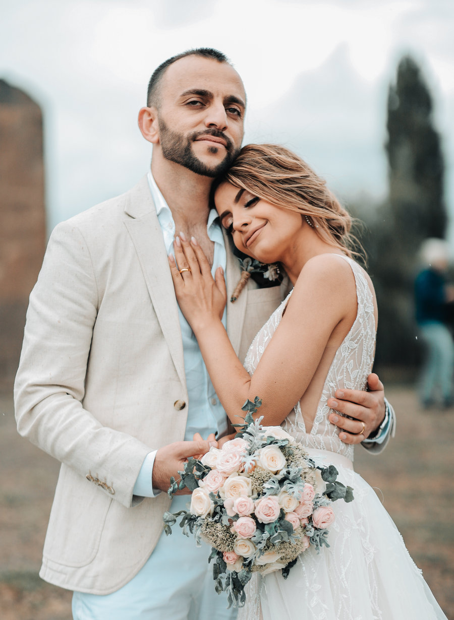 A bride resting her head on her groom’s shoulder, her bouquet in her hand