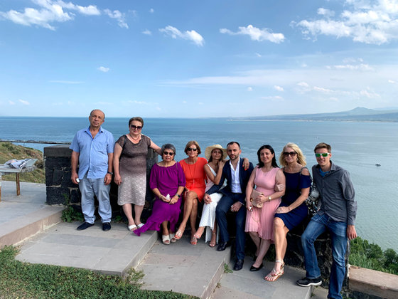 The whole party lined up along a stone terrace above a wide blue lake