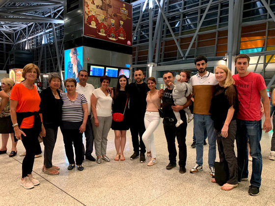 The travelling party with their hosts, and a baby in arms, in the airport terminal