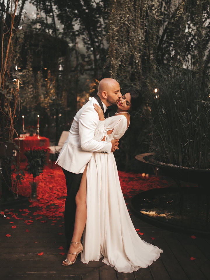 A couple in evening dress holding each other close on a candlelit terrace