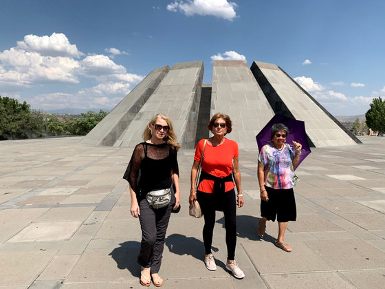 Three of the group crossing the paved plaza in front of the memorial's stele