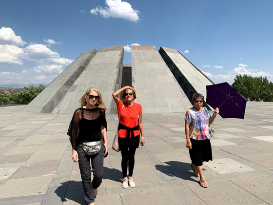 Three of the group walking in front of the memorial's tall split stone stele