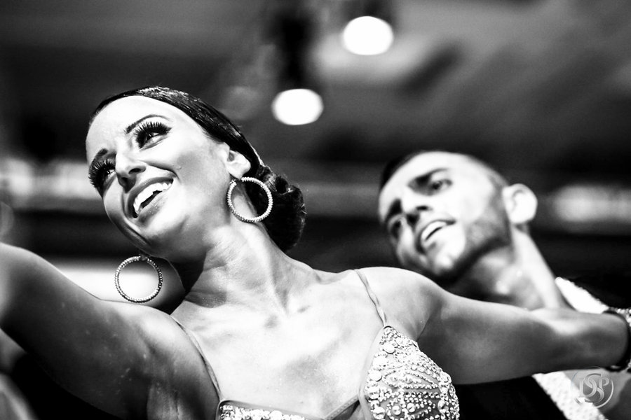A smiling couple dancing under the lights, photographed close up in black and white