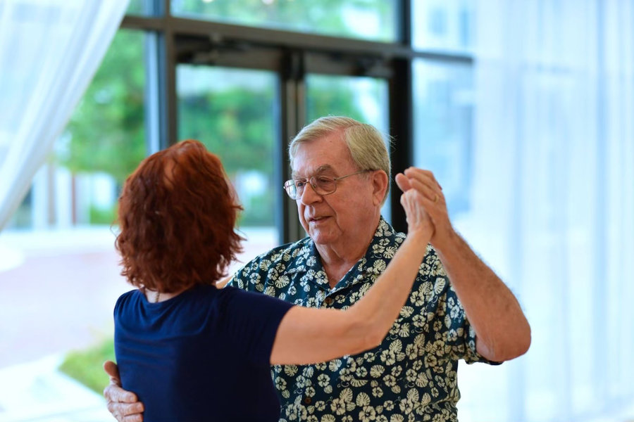 A couple dancing together in the studio's window-lit ballroom