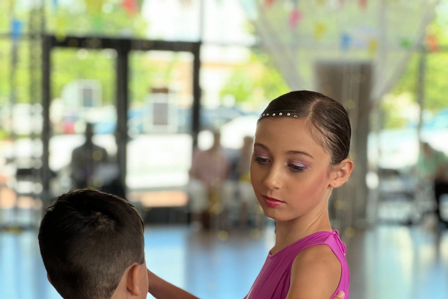 Two young students holding a closed ballroom position on the studio floor